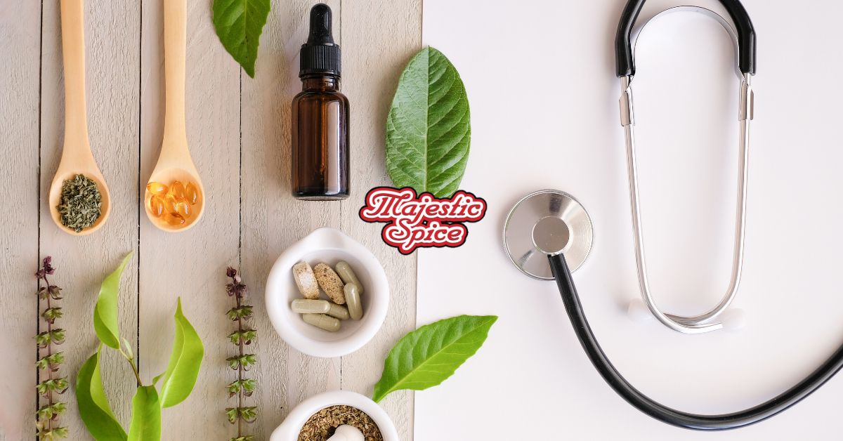 white and wood floor background with some leaves and plants as well as two wooden spoons, one with a spice and the other one with pills. We can see two white containers, one with pills and the other one with another spice. There's a dropper and a stethoscope.